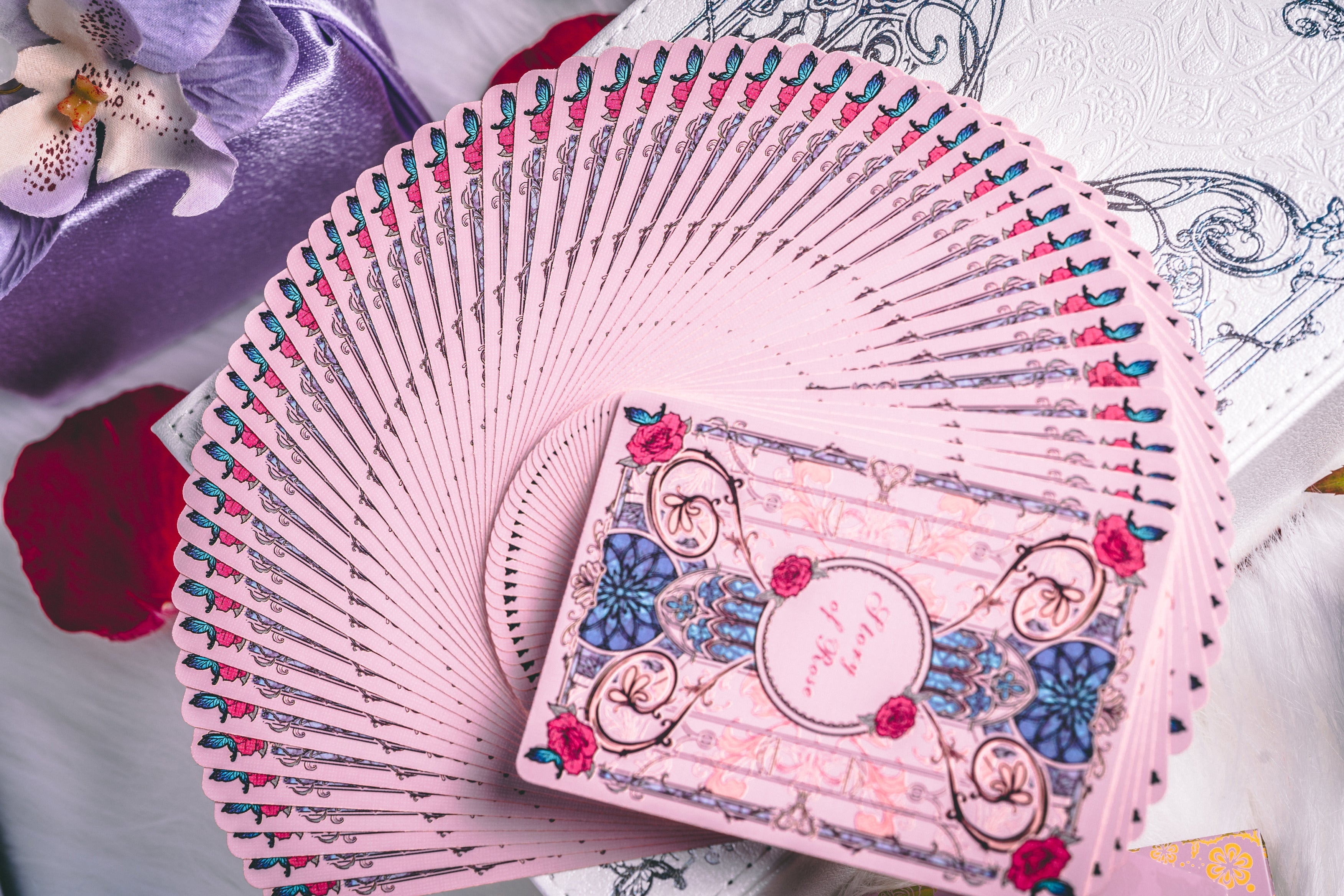 Story of Rose pink playing cards fanned beside the collector's box